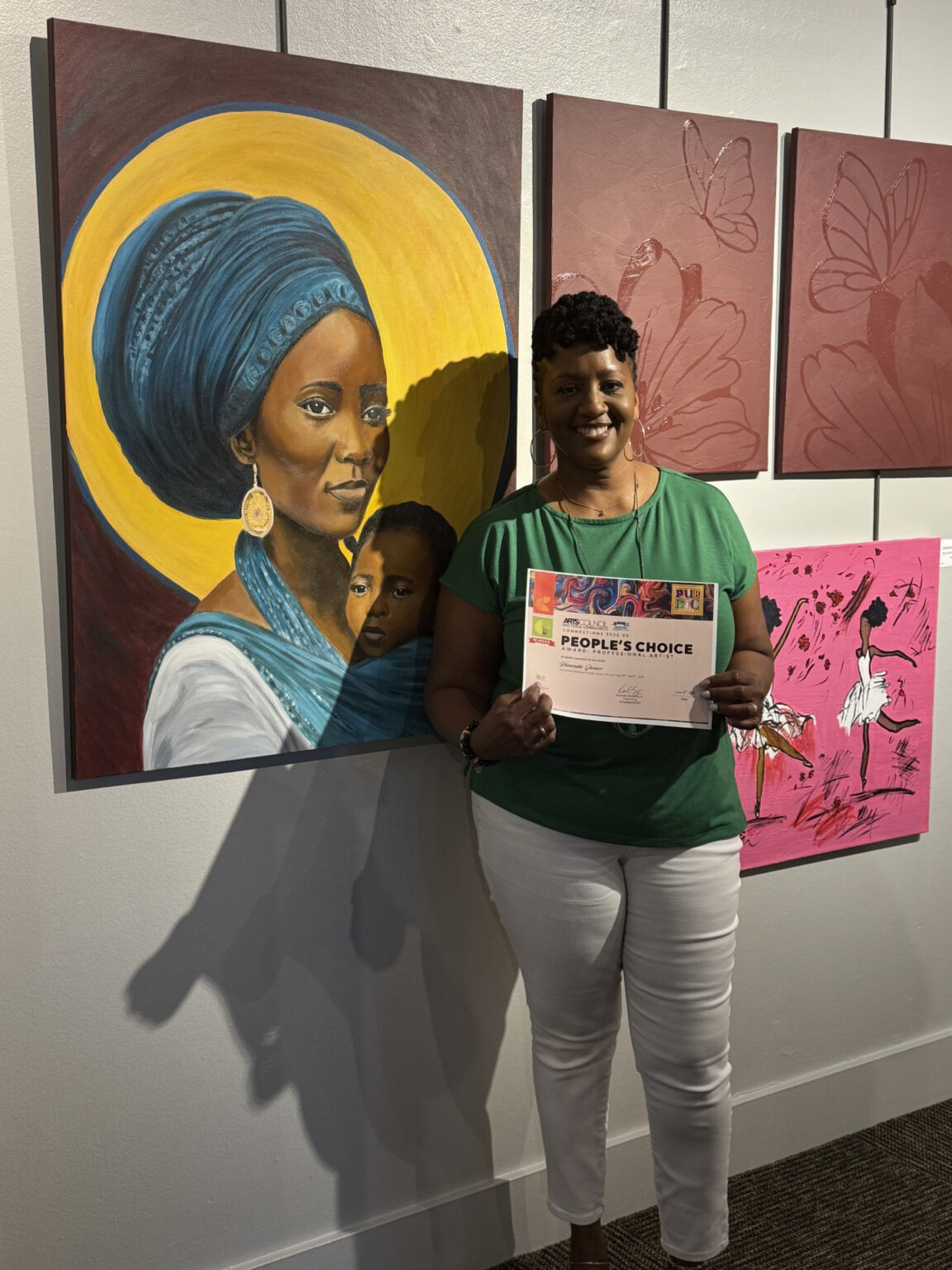 Ms. Jones holding up Award next to painting
