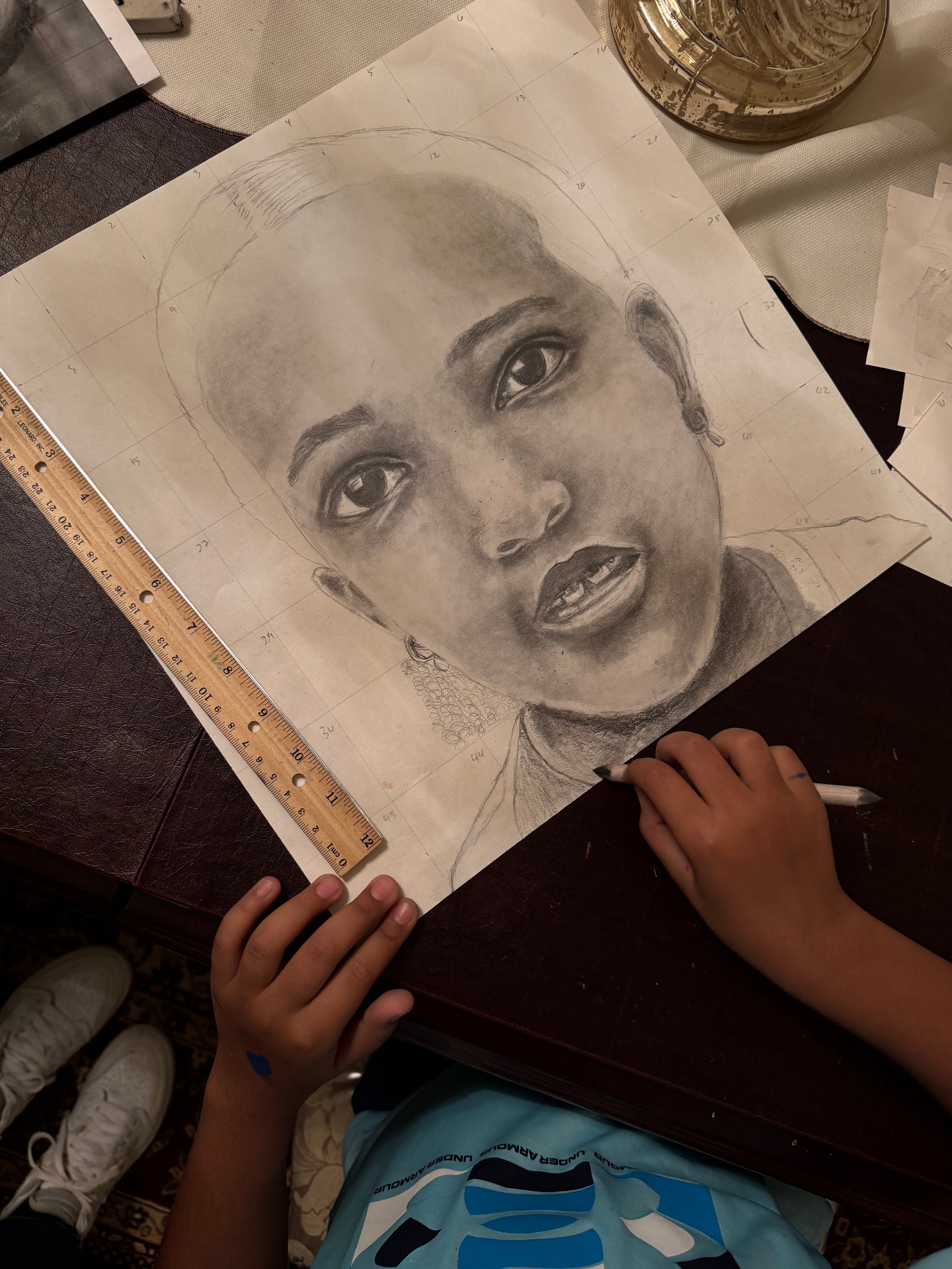 Student shading a graphite portrait with a ruler and pencil