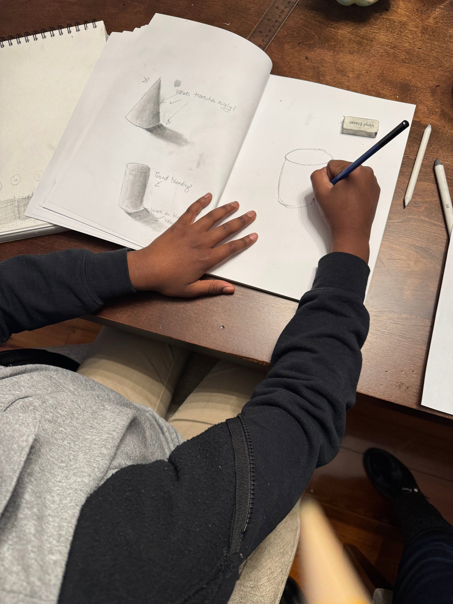 Student practicing shapes and shading in a sketchbook